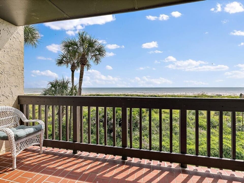 Balcony with ocean views, featuring cozy seating and lush greenery.