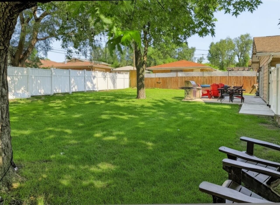 Spacious private fenced yard with mature trees and multiple outdoor gathering areas.