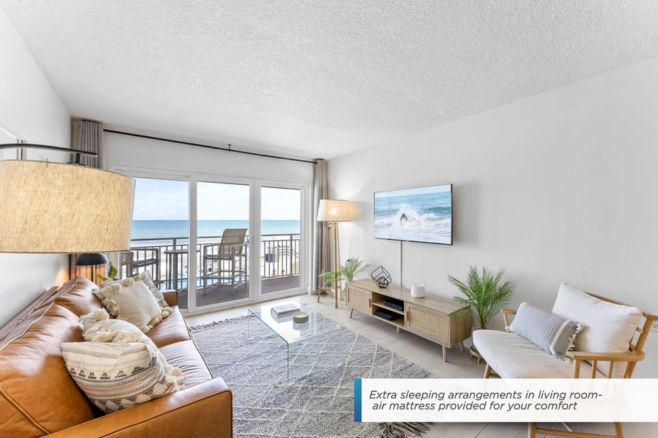 Bright and cozy living room with a large TV and oceanfront views