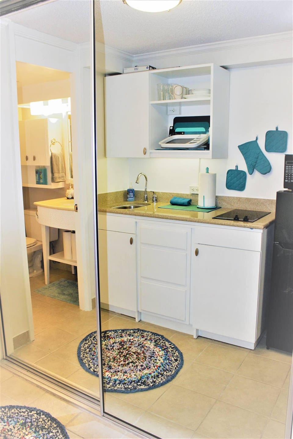 Kitchenette reflected in large closet mirror doors.