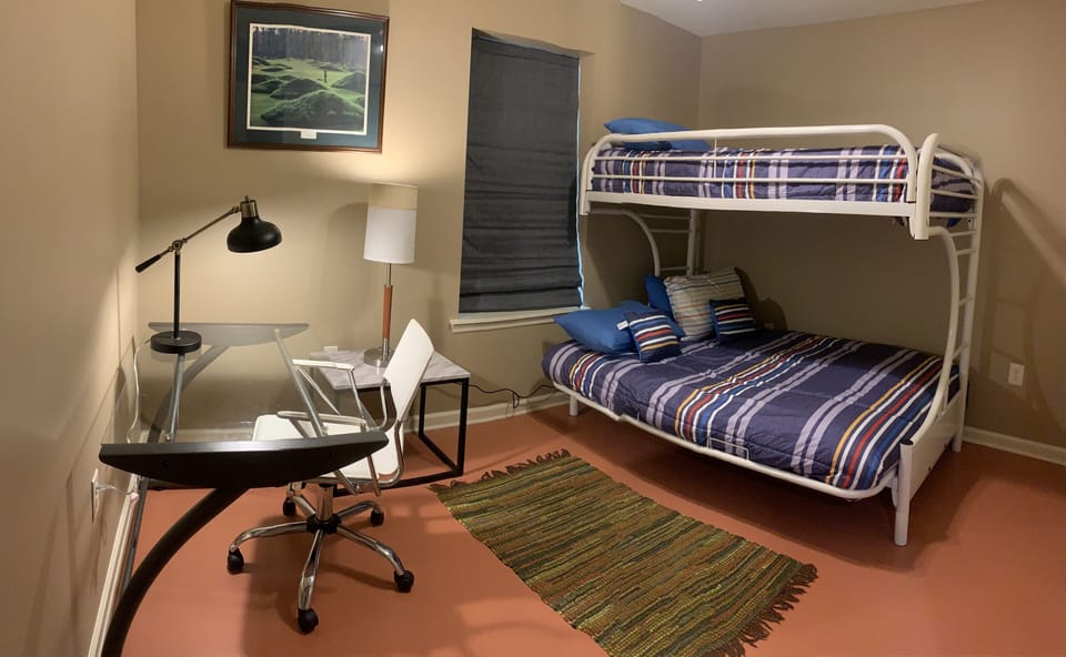 Twin size bed over full size bed., this bedroom has a desk with desk lamp.