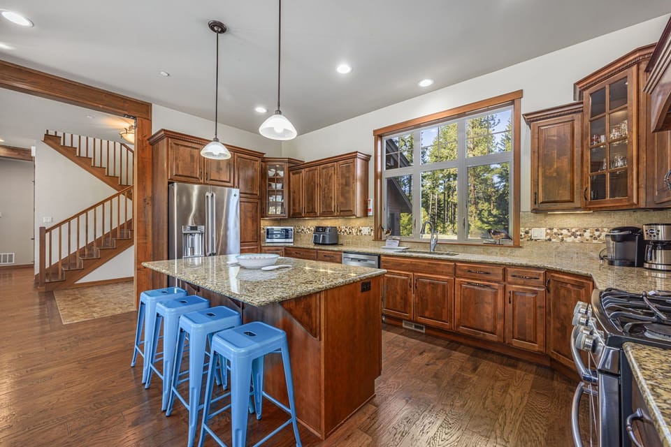Custom kitchen with rich natural wood, granite counters, and casual island seating.