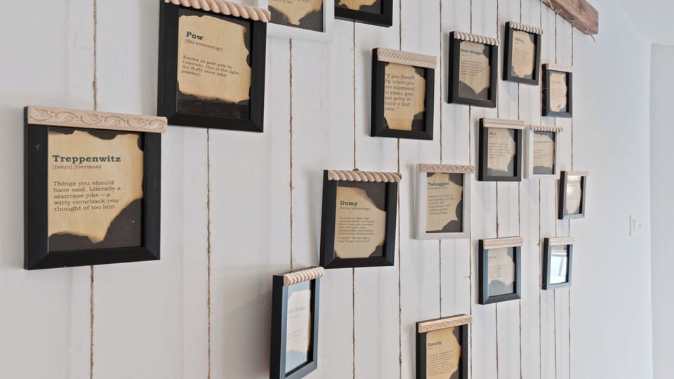 A creative display of vintage-style dictionary definitions decorates a white wood-paneled wall, adding quirky character and conversation starters to your vacation retreat.