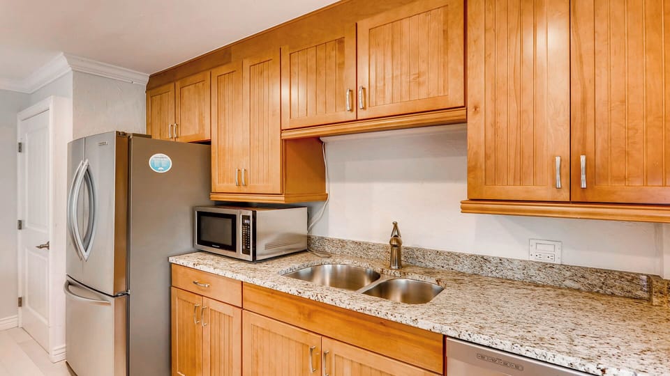 A fully equipped kitchen with granite countertops, stainless steel appliances, and warm wood cabinetry provides everything you need to prepare meals during your stay.