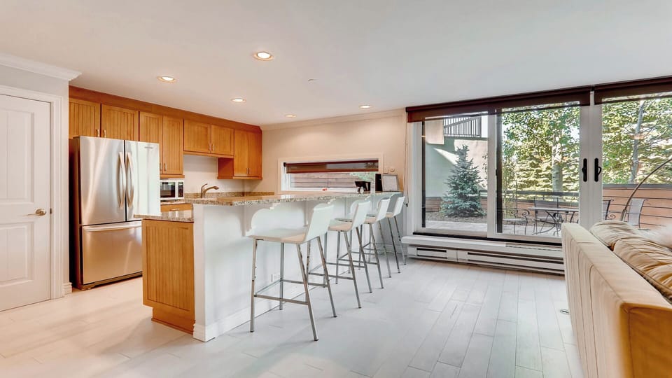 Gather around the spacious breakfast bar for morning coffee, enjoying natural light and views of the trees beyond your private balcony.