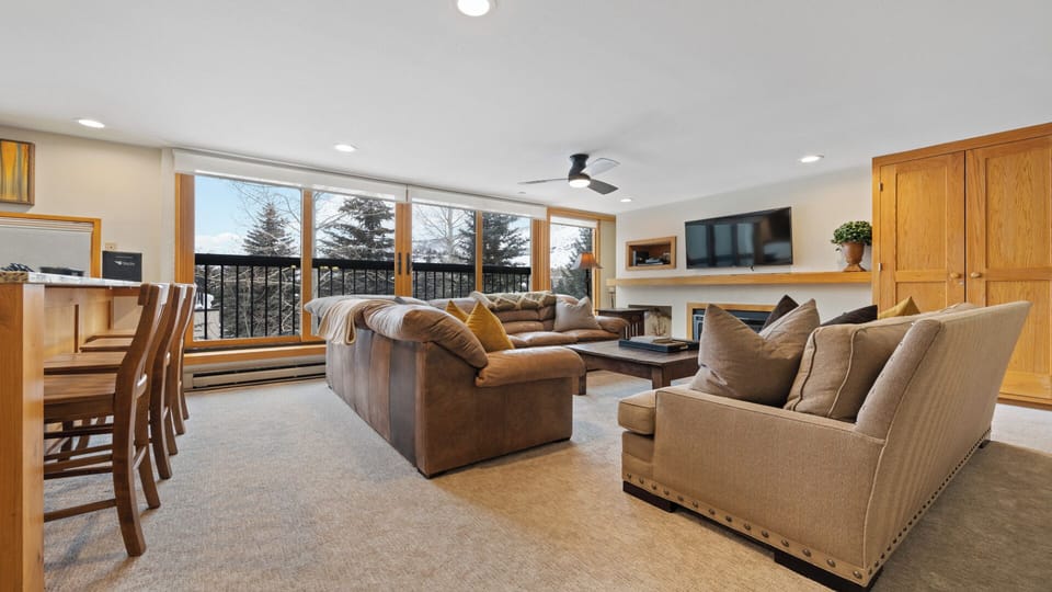Sink into plush sofas in your spacious living room, where floor-to-ceiling windows frame stunning winter mountain views and natural light streams in all day long.