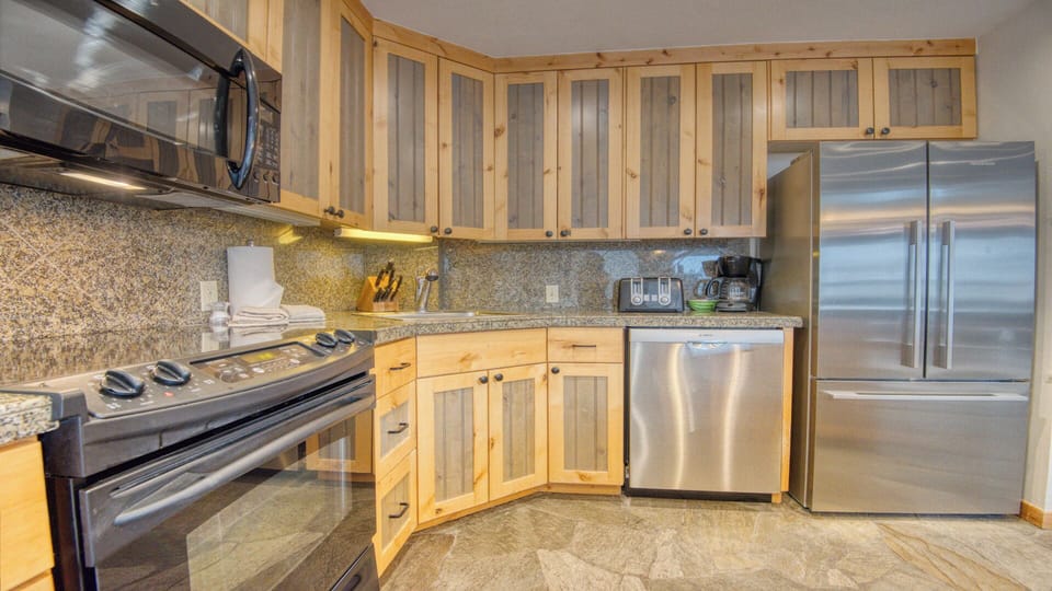 Your fully equipped kitchen features stainless steel appliances, granite countertops, and warm wood cabinetry—perfect for preparing meals and savoring your vacation mornings together.