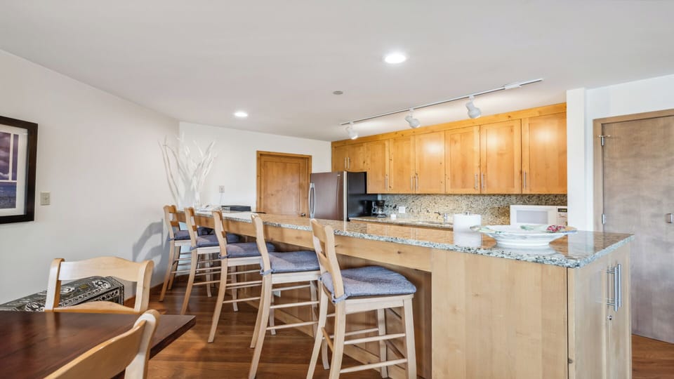 Your open kitchen and dining space invites relaxed meals with gleaming granite counters, warm wood cabinetry, and a breakfast bar perfect for morning coffee or evening gatherings.