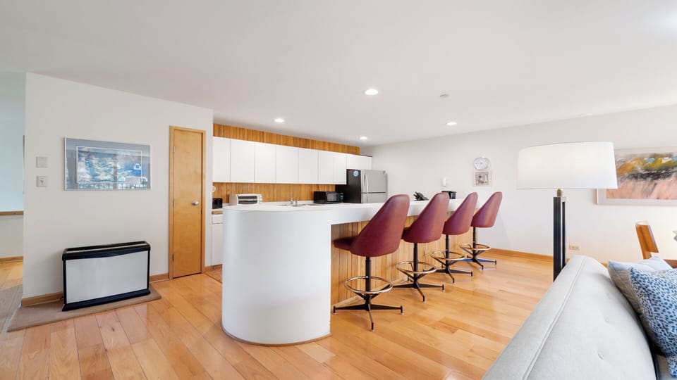 Gather around this sleek curved island—your space for morning coffee and easy meals. The open layout connects you to the kitchen and living area, perfect for staying close while you cook and relax.