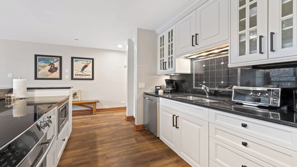 Picture yourself preparing meals in this fully equipped kitchen, featuring sleek white cabinetry, granite countertops, and stainless steel appliances—your home base for unforgettable vacation moments.