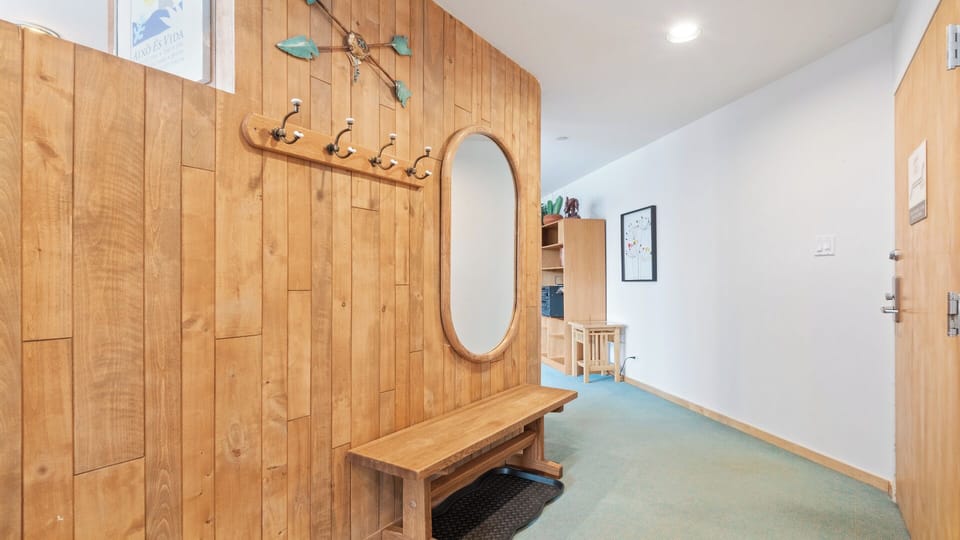 An inviting entryway with warm wood accents, coat hooks, and a full-length mirror to help you settle in and feel at home the moment you arrive.