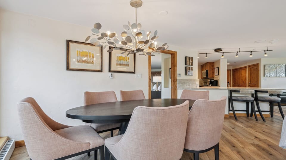 Gather around your elegantly appointed dining table, where a stunning statement chandelier casts warm light over spacious seating and open flow to your fully equipped kitchen.