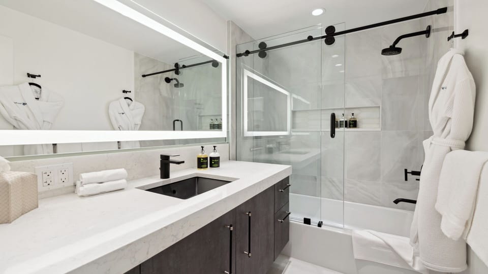 Step into a modern, spa-like bathroom with sleek fixtures, plush robes, and a spacious glass-enclosed shower—your own serene retreat for ultimate relaxation.