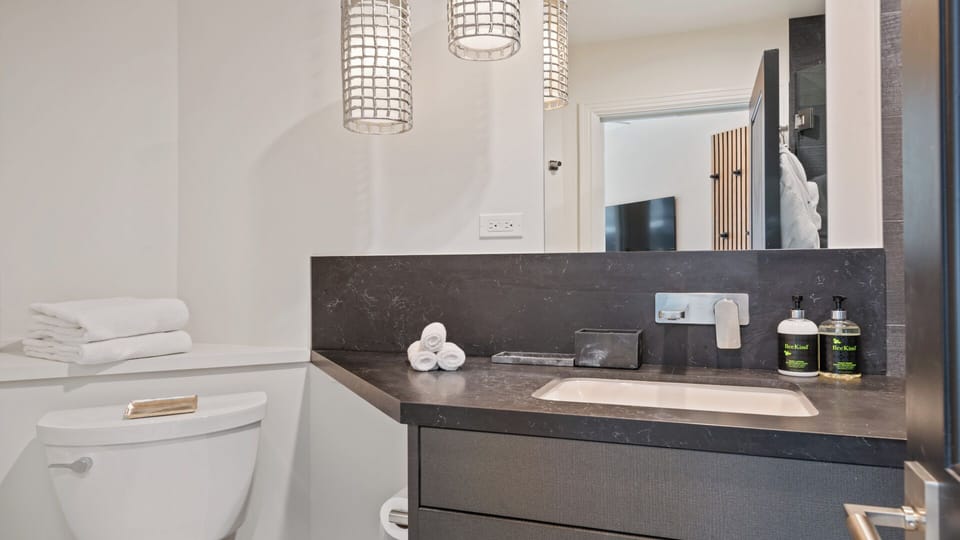Your private bathroom features a sleek marble vanity with modern fixtures, fresh towels, and premium toiletries waiting for you. The space is bright, clean, and thoughtfully designed for your comfort.