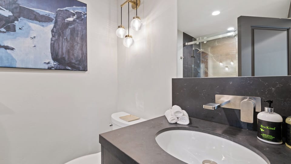 Your private bathroom features modern fixtures, a sleek vanity with fresh towels, and contemporary lighting—perfectly appointed for your comfort and convenience.