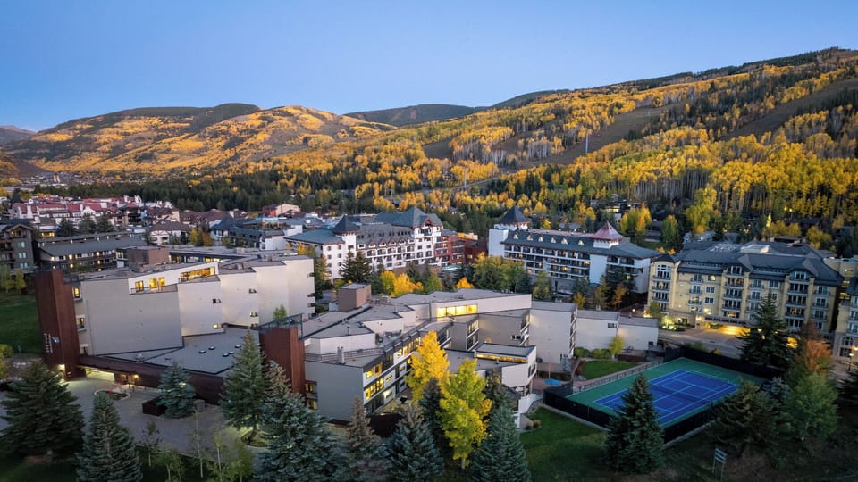 An alpine resort town nestled beneath golden autumn hillsides, offering access to mountain recreation, tennis courts, and scenic landscapes.