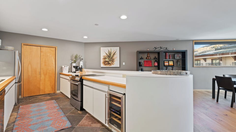 Your gourmet kitchen features sleek white cabinetry, warm wood countertops, and stainless steel appliances, plus a wine cooler to enhance your mountain getaway experience.