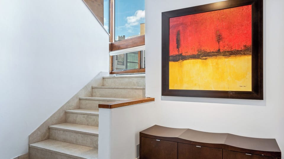 Bright stairwell with bold artwork adds character and warmth to your private space, connecting living areas under natural daylight streaming through expansive windows.