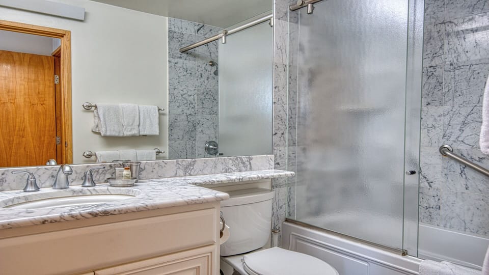 Freshen up in this elegant marble bathroom, complete with a glass-enclosed shower, dual vanity, and plush towels—your private retreat after a day exploring.