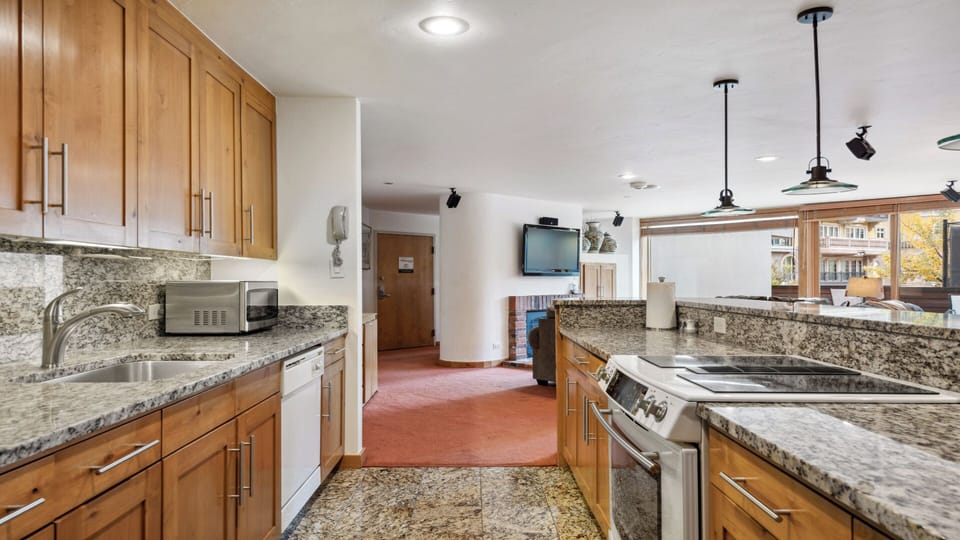 You'll love preparing meals in this spacious, well-equipped kitchen with granite counters, modern appliances, and natural light streaming through the window overlooking the neighborhood.