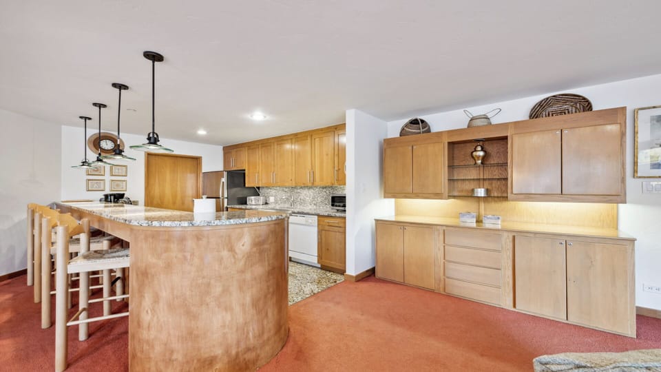 Your spacious kitchen features warm wood cabinetry, granite countertops, and a curved island with bar seating—perfect for preparing meals and gathering with loved ones.