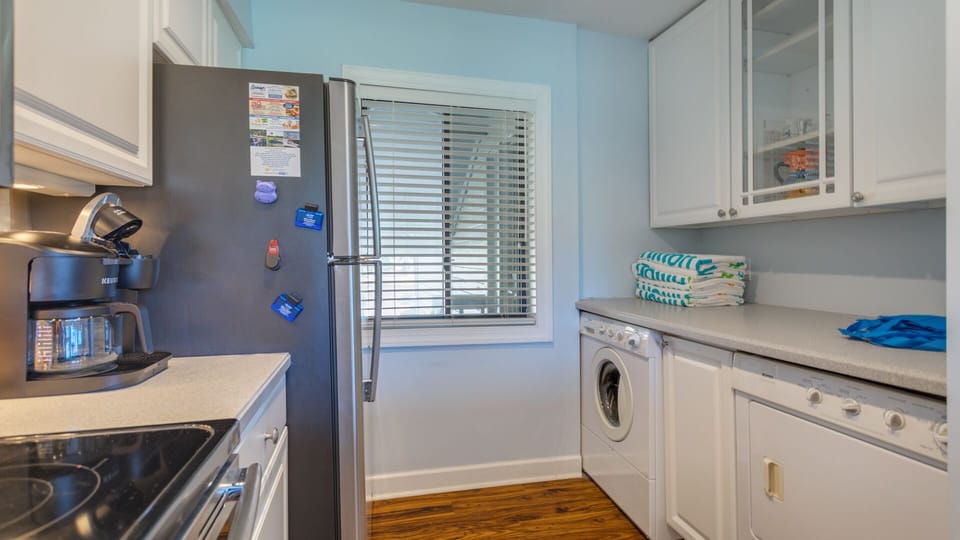 A convenient laundry area is tucked into the kitchen, featuring a full-size washer and dryer, ample cabinetry, and natural light.