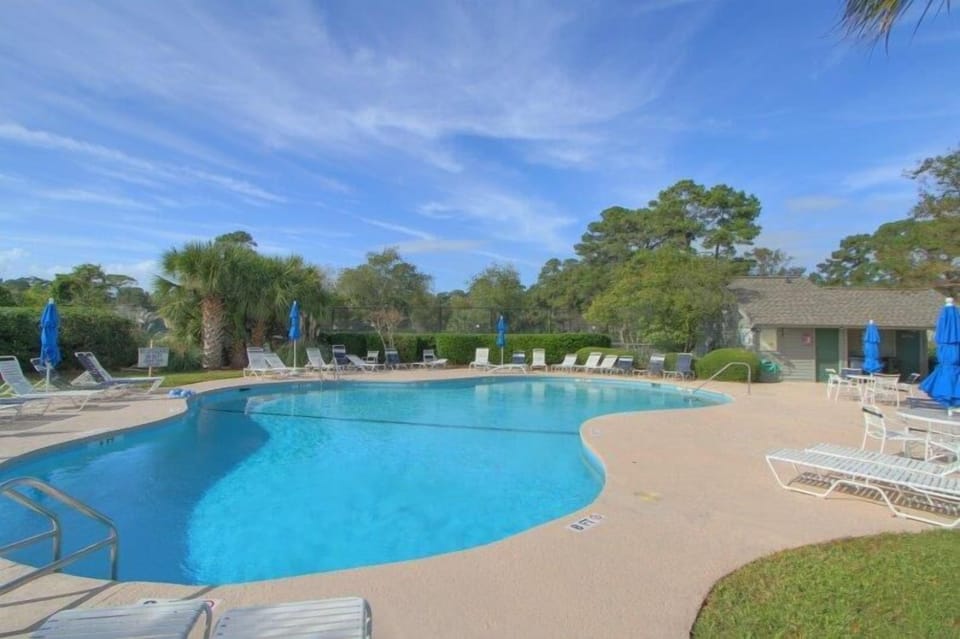 The community pool offers a resort-style setting surrounded by lush trees and open skies—perfect for cooling off after a day at the beach.