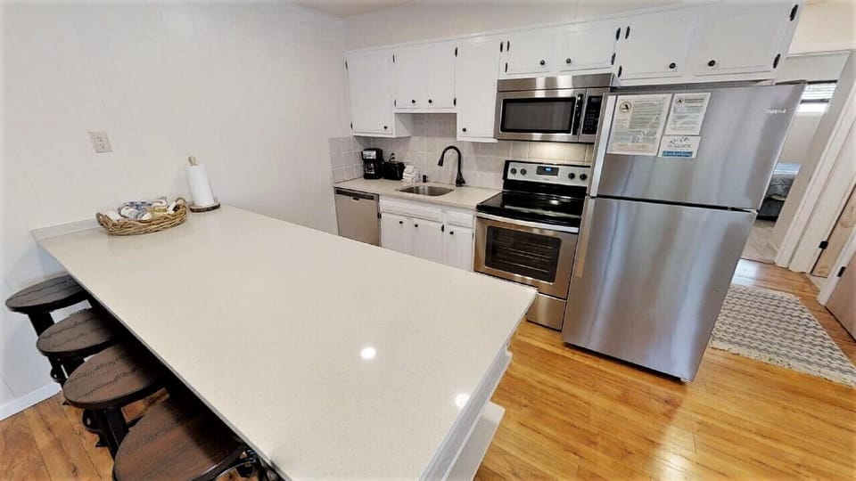 This bright kitchen invites you to prepare meals with ease. Stainless steel appliances, white cabinetry, and a spacious island create a clean, functional space for your vacation cooking adventures.