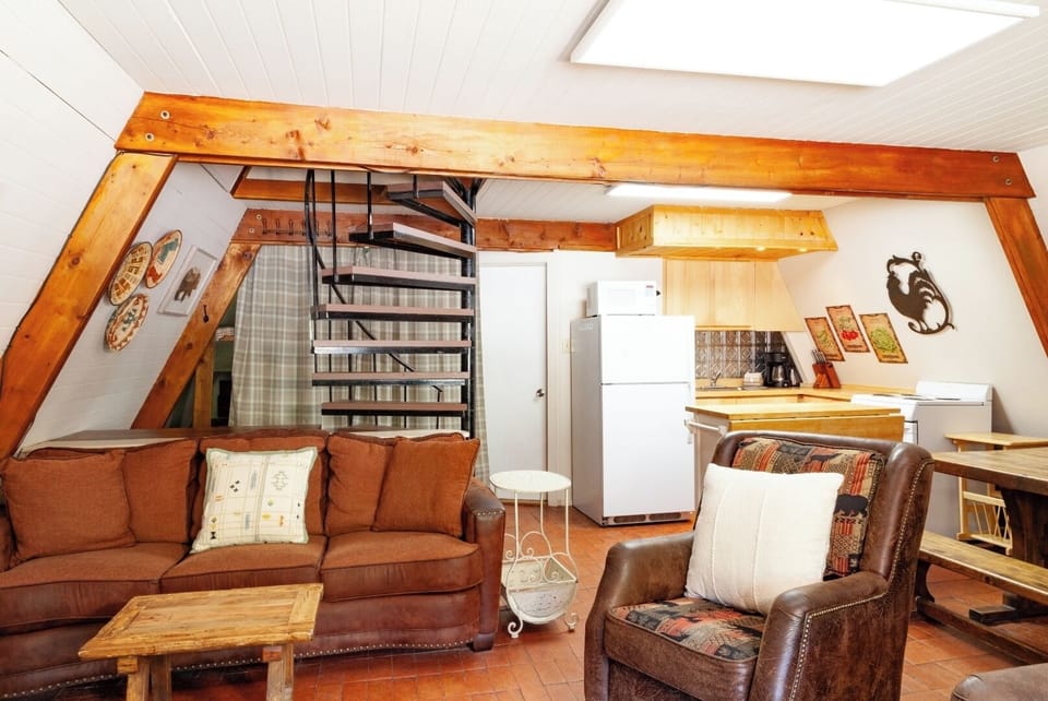 Unwind in your cozy A-frame retreat with exposed beams, a comfy sectional sofa, and a spiral staircase to your private loft—your charming mountain escape awaits.