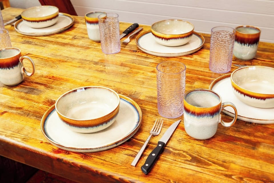 Your rustic wooden dining table is beautifully set with artisan earthenware dishes and textured glassware, inviting you to gather for memorable meals together.