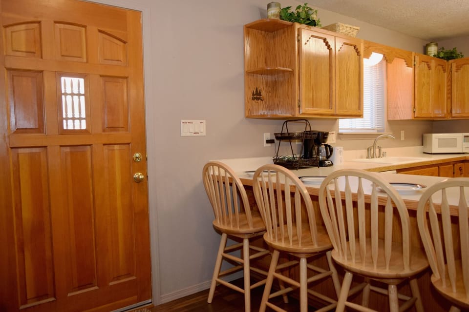 Gather around the breakfast bar with family in this warm, sunlit kitchen. Natural wood tones and open shelving create a cozy, home-away-from-home feel where you'll love starting your mornings.