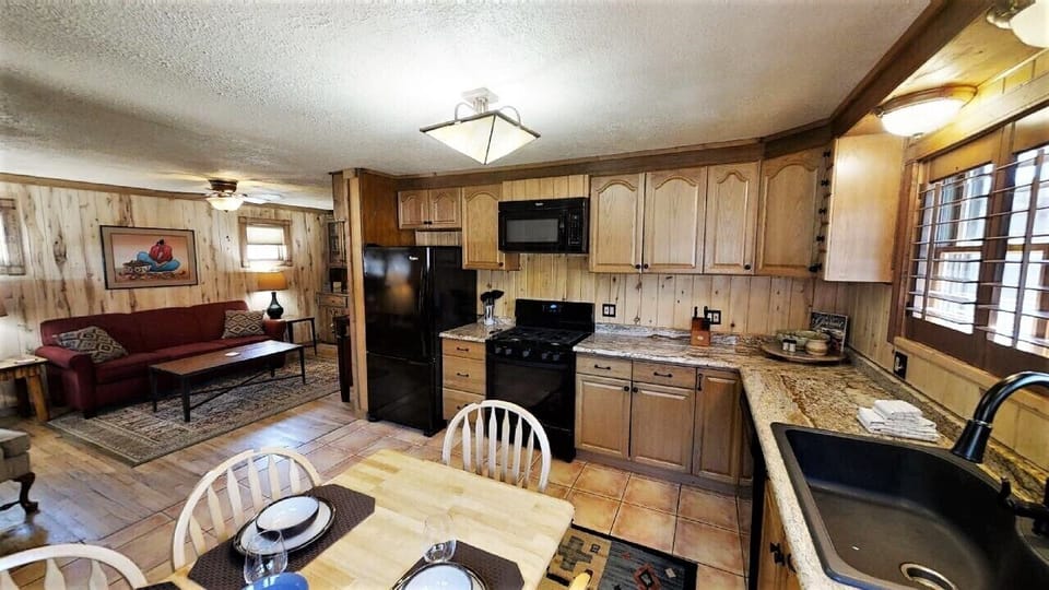 Step into your cozy open-plan retreat, where rustic wood paneling and granite counters blend seamlessly with a fully-equipped kitchen and inviting living area—your home away from home.