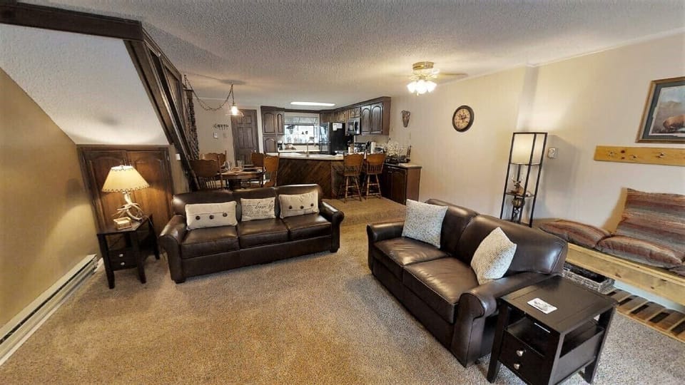 Sink into plush leather sofas in your spacious living area, where rustic wood accents and warm lighting create a cozy mountain retreat atmosphere perfect for unwinding after your adventures.