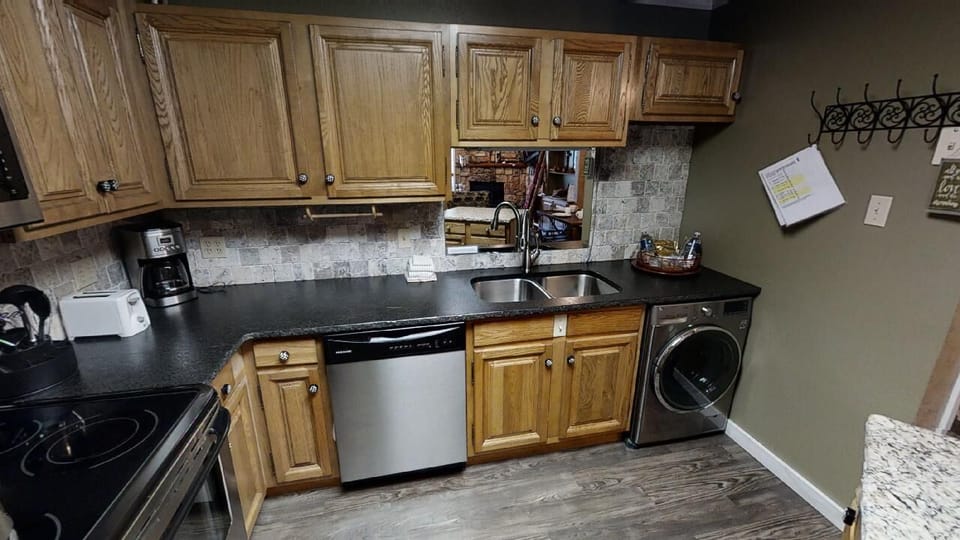 Your well-appointed kitchen awaits with a full stove, dishwasher, and in-unit washer, all surrounded by warm wood cabinetry and classic tile backsplash for effortless home-style cooking and convenience.