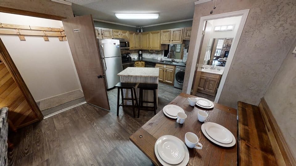 Your fully equipped kitchen features modern appliances, a convenient island with seating for quick meals, and a separate dining table set for four—perfect for gathering over home-cooked favorites.
