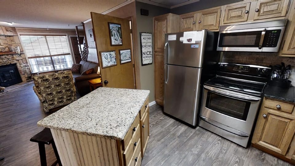 Your fully equipped kitchen features granite countertops, stainless steel appliances, and everything you need to cook comfortably, with an inviting living space just beyond.