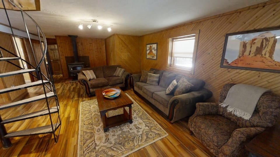 Sink into plush seating in this warm, wood-paneled living room where rustic charm meets comfort. Gather around the coffee table or unwind on cozy sofas after exploring nearby attractions.
