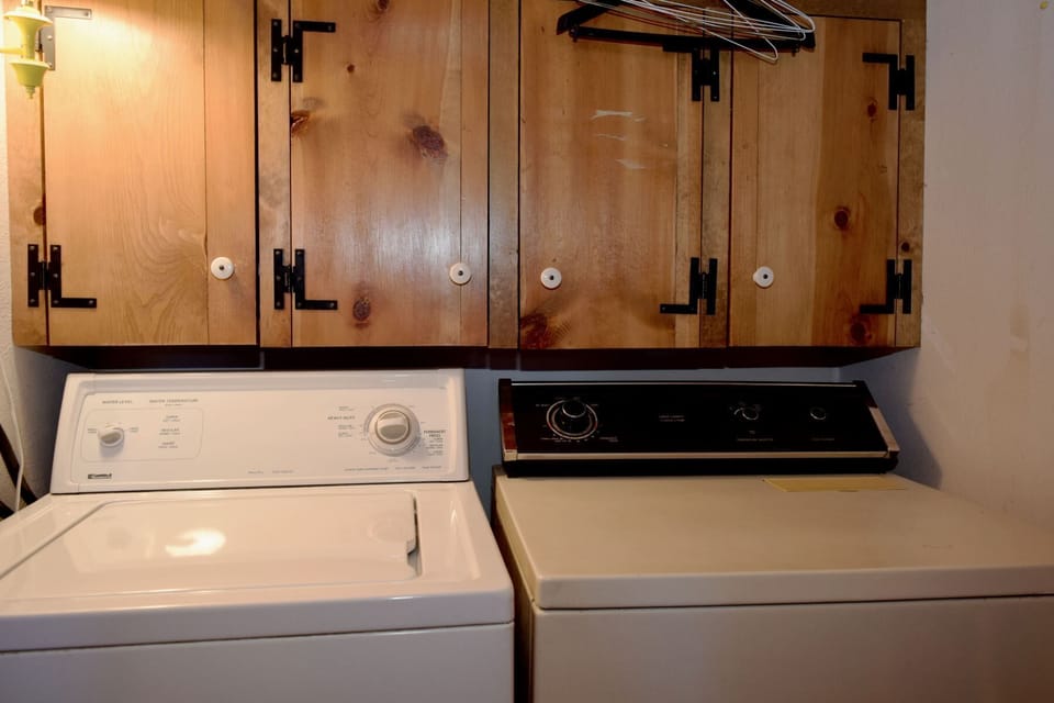 Your laundry stays effortless with a full-size washer and dryer tucked under rustic wooden cabinetry—ample storage for all your essentials during your stay.
