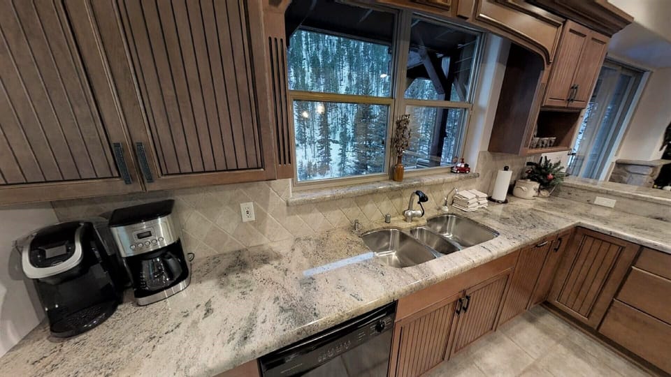 Whip up your favorite meals in this fully-equipped kitchen, complete with granite countertops, modern appliances, and serene snowy forest views through the window.