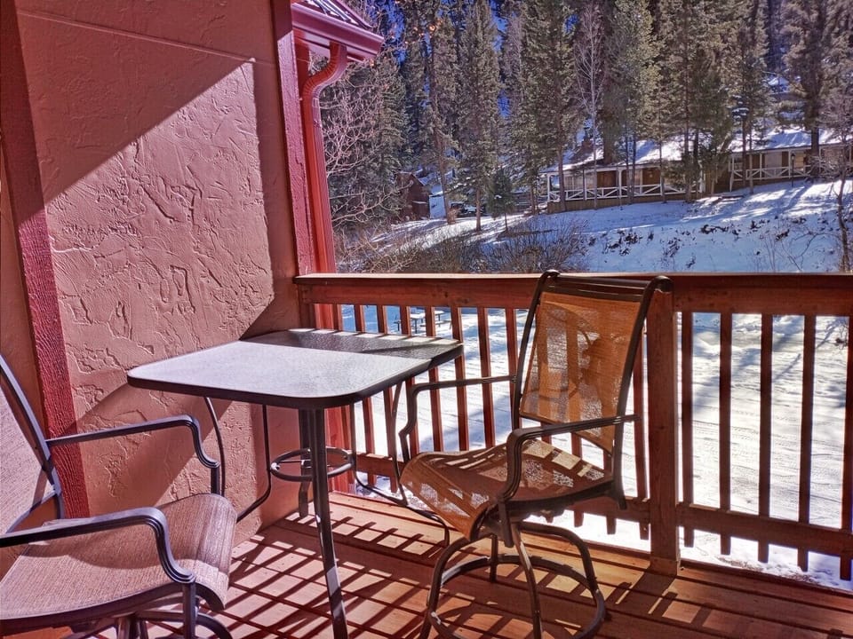 Step onto your private balcony and breathe in crisp mountain air while sunlight dances across snowy pines. Sip morning coffee at your cozy table surrounded by peaceful winter beauty.