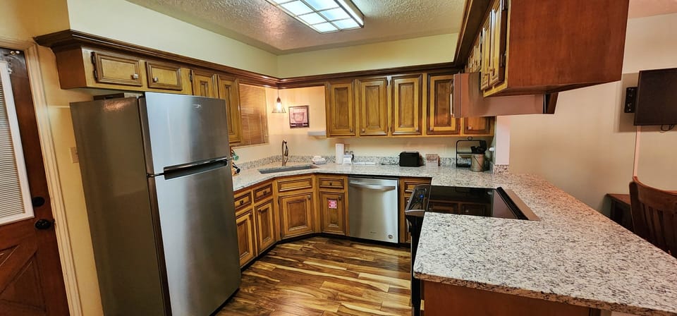 Your fully equipped kitchen features granite countertops, stainless steel appliances, and warm wood cabinetry—perfect for preparing meals and gathering with loved ones during your stay.