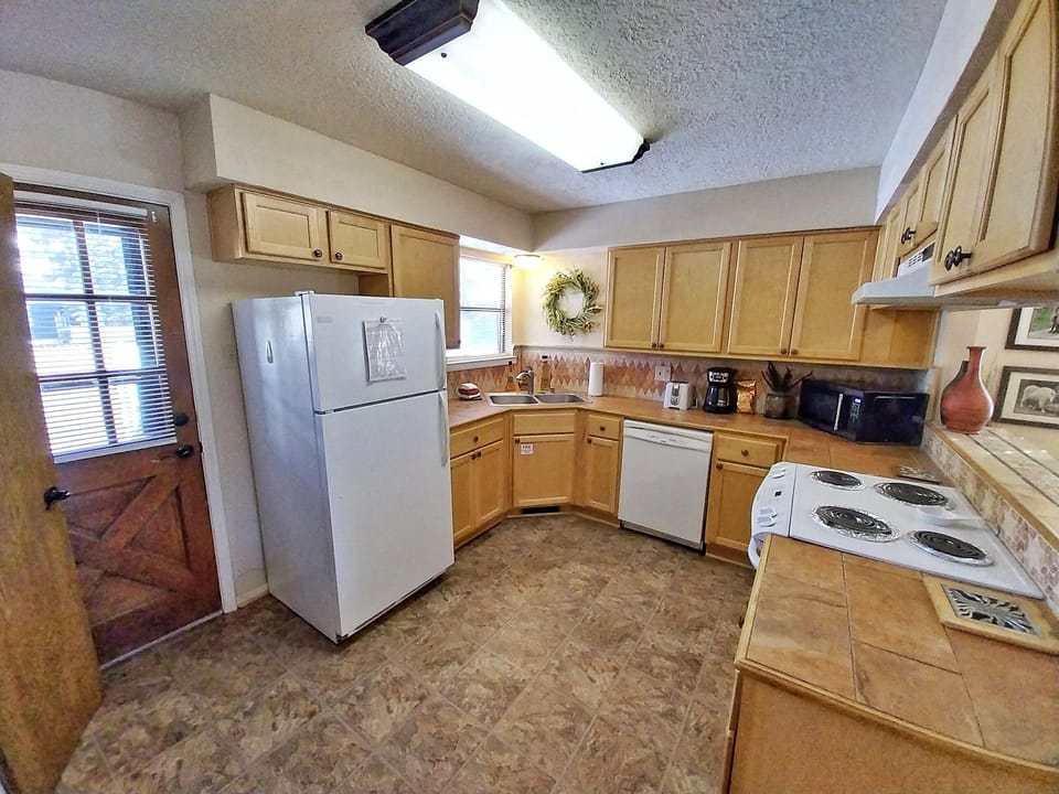 Gather around this fully-equipped kitchen where you can whip up hearty home-cooked meals during your stay. The bright skylight and warm wood cabinetry create a welcoming space for your culinary adventures.