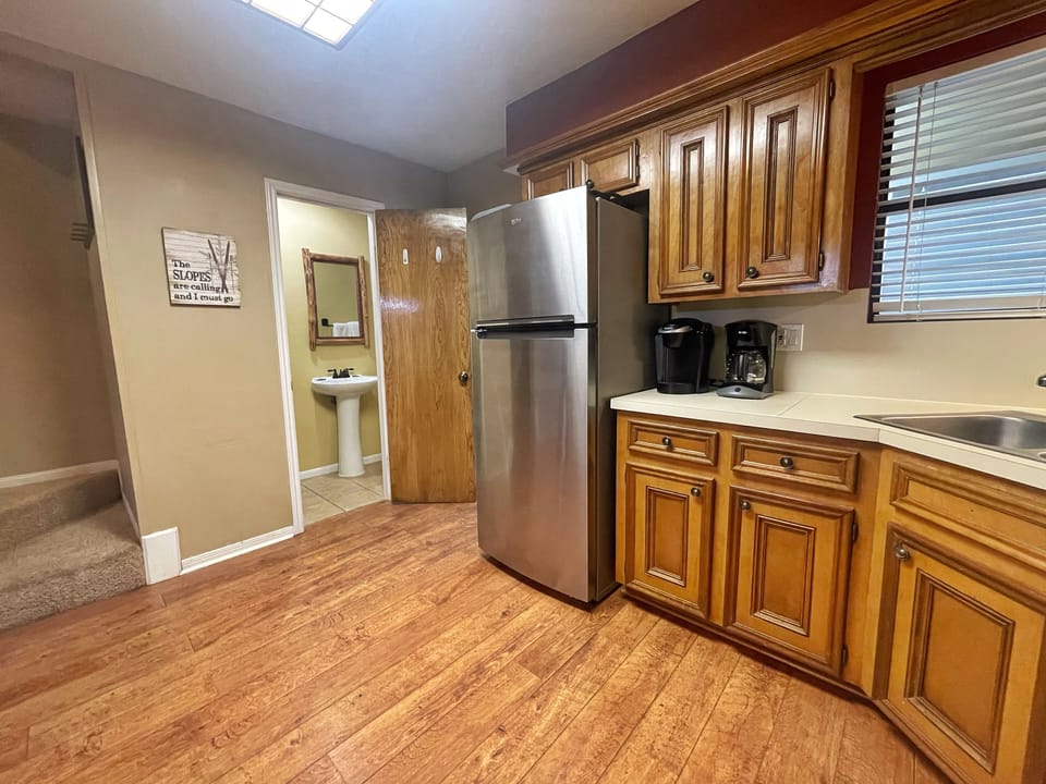 Your fully equipped kitchen features stainless steel appliances, warm wood cabinetry, and plenty of counter space for preparing meals. Natural light streams in from above, creating a bright and welcoming space for your stay.