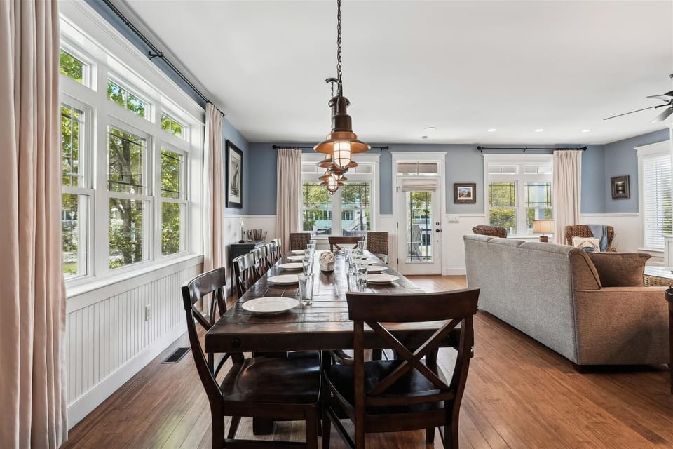221 Wellington Parkway Open Concept Living and Dining Room View - An expansive perspective showing the flow from the formal dining area into the adjacent living room, featuring polished hardwood floors and white wainscoting.