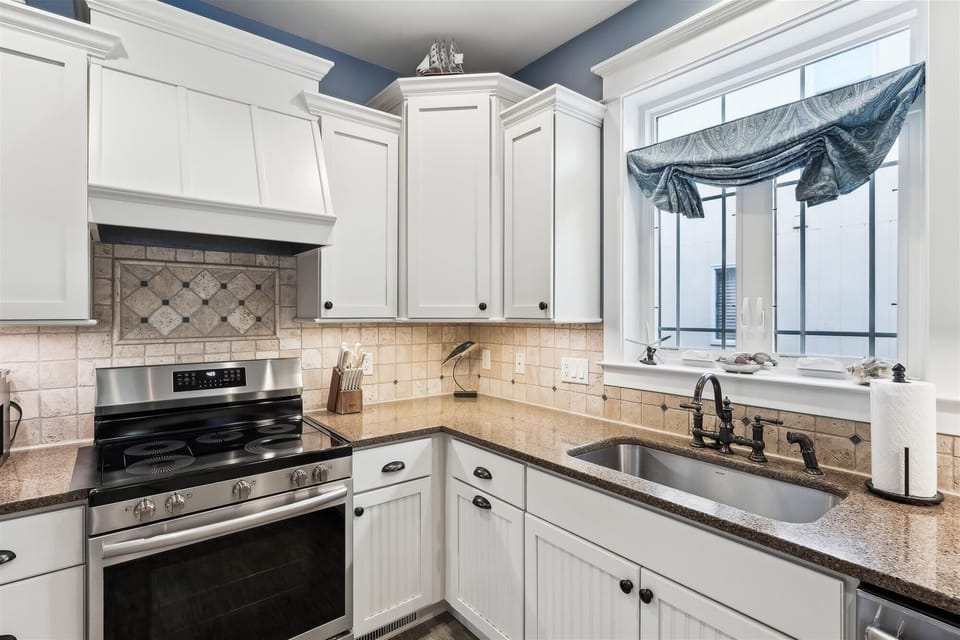 221 Wellington Parkway Kitchen Detail with Subway Tile Backsplas - A close-up view of the kitchen workspace highlighting the patterned tile backsplash above the range, an undermount sink, and ample counter space.