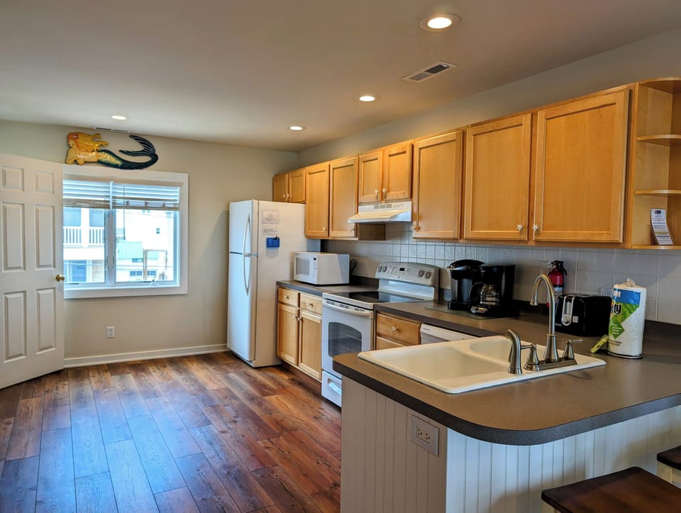 38901 Bunting Avenue Modern Kitchen with Breakfast Bar Seating - A view of the kitchen highlighting the breakfast bar with stool seating and wide windows providing natural light.
