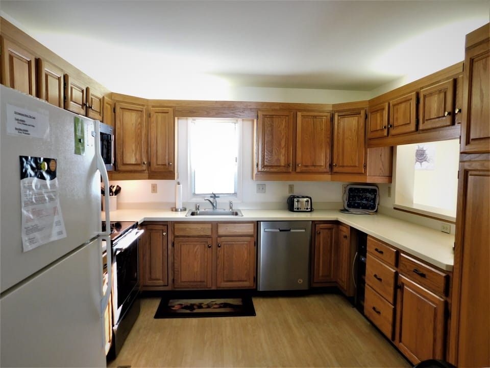 324 Seabreeze, The Canal - Kitchen Overview & Appliances - Spacious kitchen at 324 Seabreeze, The Canal, highlighting the warm oak-toned cabinetry, white refrigerator, and efficient wrap-around countertop layout.