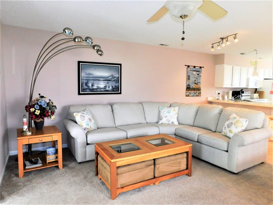 33 Thistle Lane - Cozy Living Area - Inviting living room at 33 Thistle Lane featuring a large L-shaped sectional, a unique arched floor lamp, and a warm, carpeted space for relaxation.