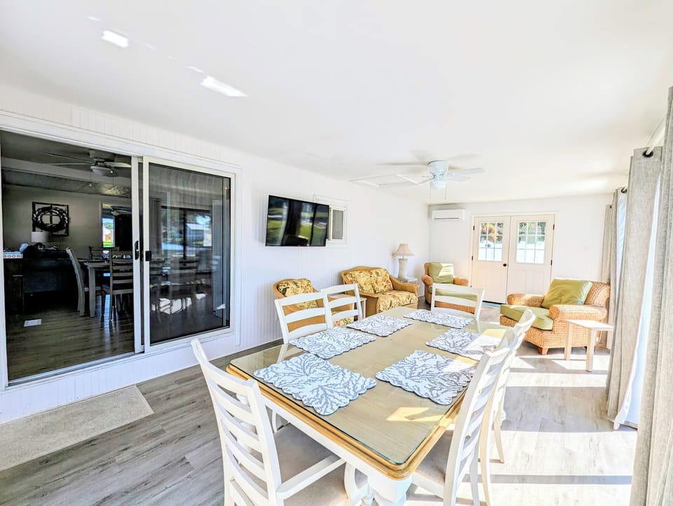 38166 Bow S38166 Bow Street, Ocean Viewtreet, Ocean View -Sunroo - Spacious sunroom featuring comfortable wicker-style seating and a wall-mounted TV, ideal for relaxing after a day at the beach.
