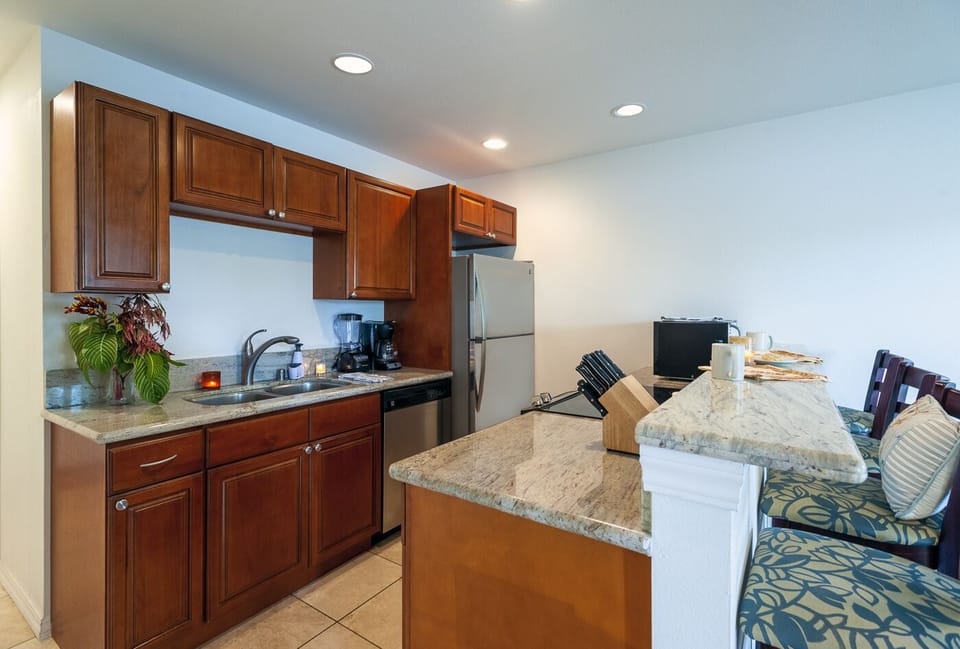 Kitchen | Kauai Kailani 218 - The updated kitchen is small but mighty, with everything you need to whip up a meal! There's a full size fridge/freezer, dishwasher, microwave, coffee pot, toaster, pots/pans, dishes/utensils, and a small selection of basic cooking supplies.